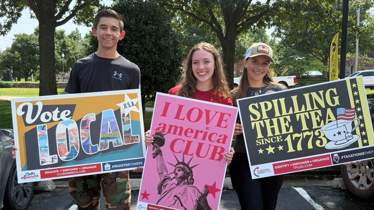 Teenagers holding signs supporting Turning Point USA and American values.