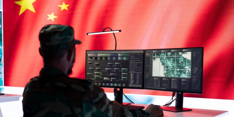 A Chinese soldier sitting at a desk, looking at a computer.