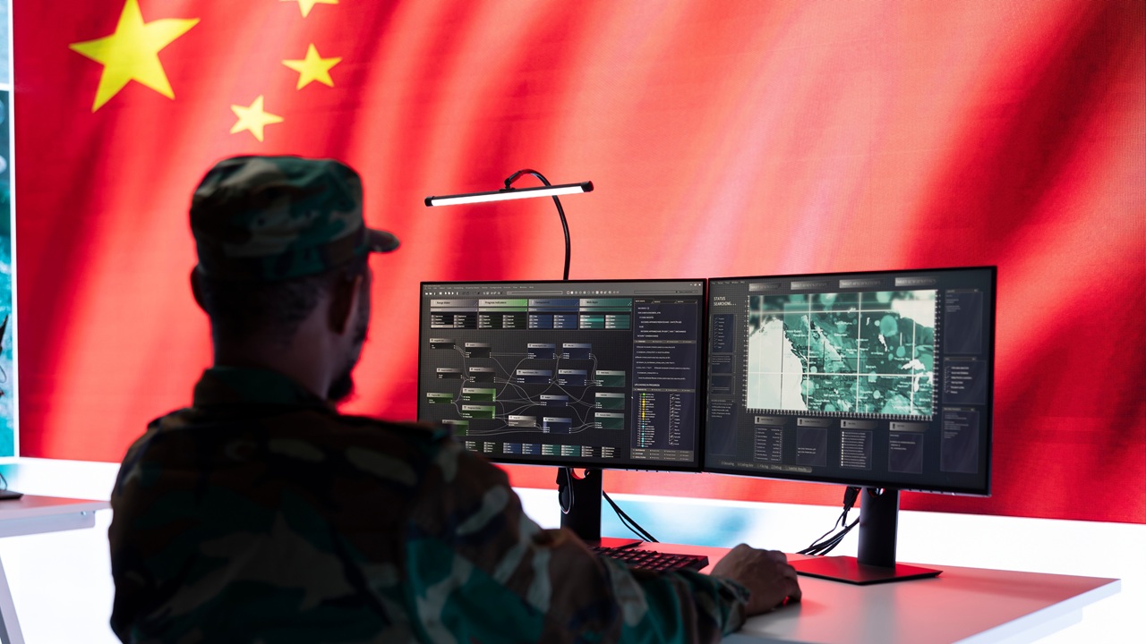 A Chinese soldier sitting at a desk, looking at a computer.
