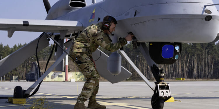 Spc. John Grayson, an MQ-1C Unmanned Aircraft System repairer and crew chief assigned to the Grey Eagle Company, 1st Battalion, 501st Aviation Regiment, Combat Aviation Brigade, 1st Armored Division, conducts pre-flight operations for the MQ-1C Gray Eagle at Forward Operating Site Powidz, Poland, March 25, 2025.