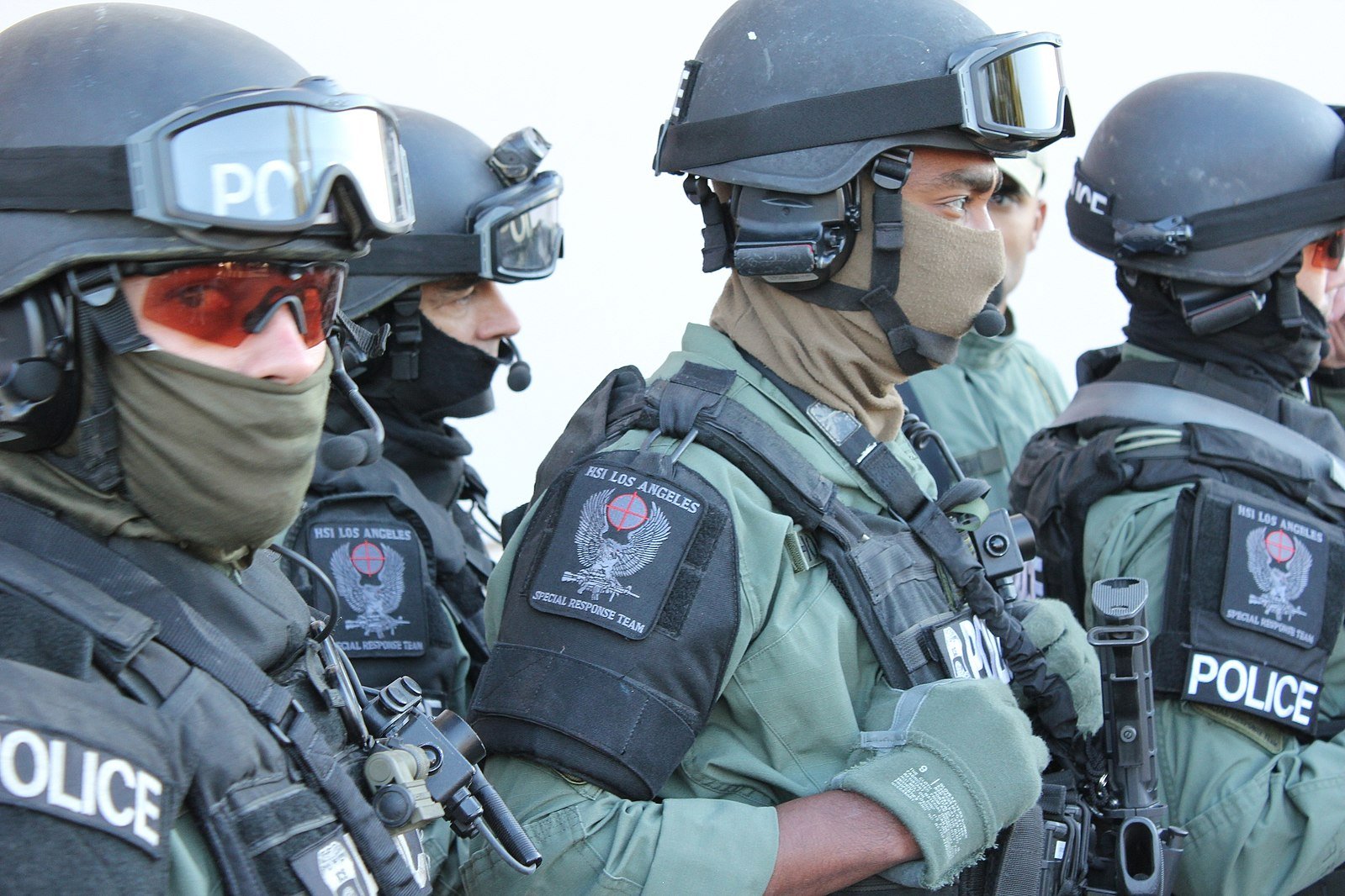 A group of armed law enforcement officers in tactical gear stands ready, showcasing their specialized response team uniforms and equipment.