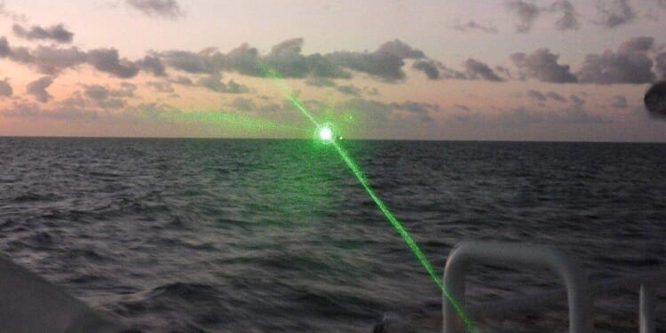 A Chinese Coast Guard ship firing a laser at a Philippine Coast Guard vessel.