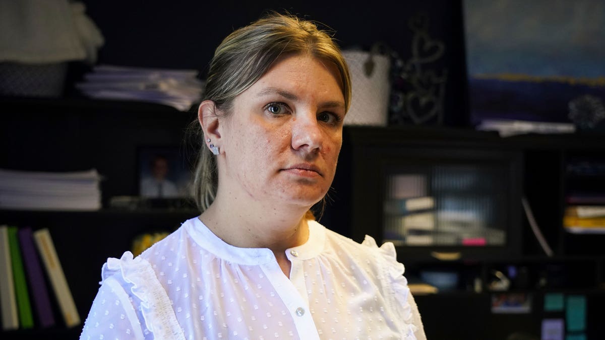 Aimee Bock standing in front of a bookshelf, looking into the camera.