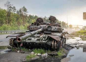 A destroyed Russian tank sits on the road.