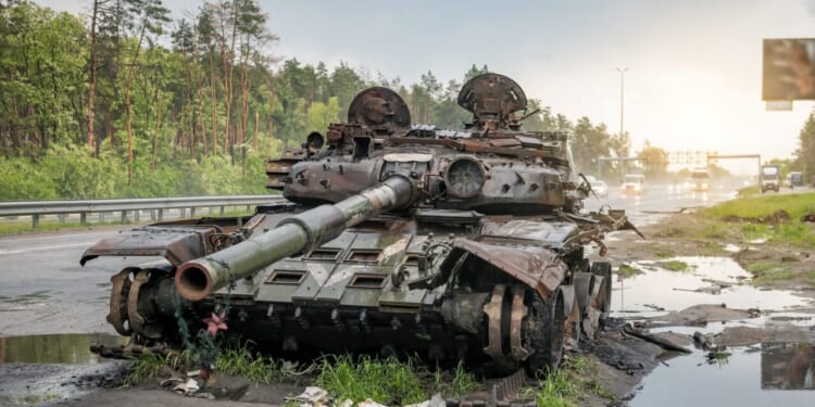 A destroyed Russian tank sits on the road.