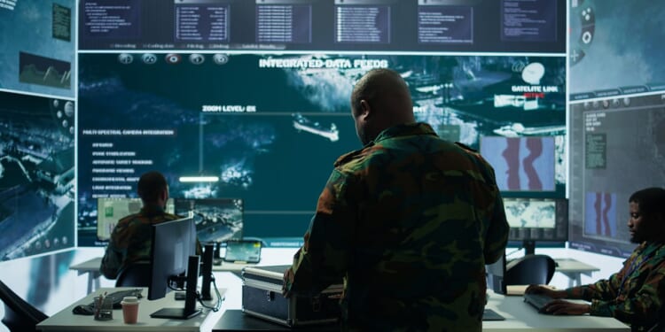 Military specialist in command post uses advanced technology and high tech gear to gather intelligence from satellite imagery and computer surveillance systems to communicate information. redefining economic warfare