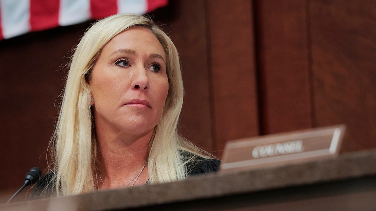 Rep. Marjorie Taylor Greene looking on.