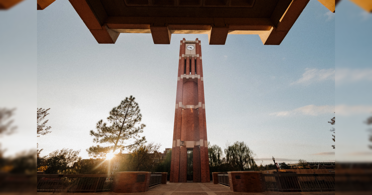 Clock tower at sunset surrounded by trees, showcasing architectural design and serene atmosphere.