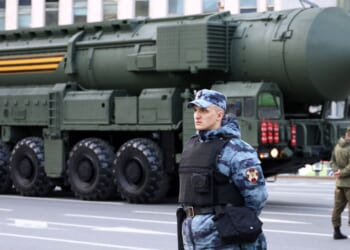 Soldiers of Russian military forces standing on background of strategic missile system "Yars" on city street, nuclear weapon.