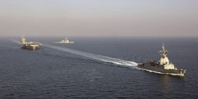 A Spanish F-100 frigate at sail near American aircraft carriers.