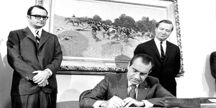 View of President Richard Nixon signing the Clean Air Act of 1970 at the White House. Looking on are William Ruckelshaus, Administrator of the Environmental Protection Agency (left), and Russell E. Train, Chairman of the Council on Environmental Quality.