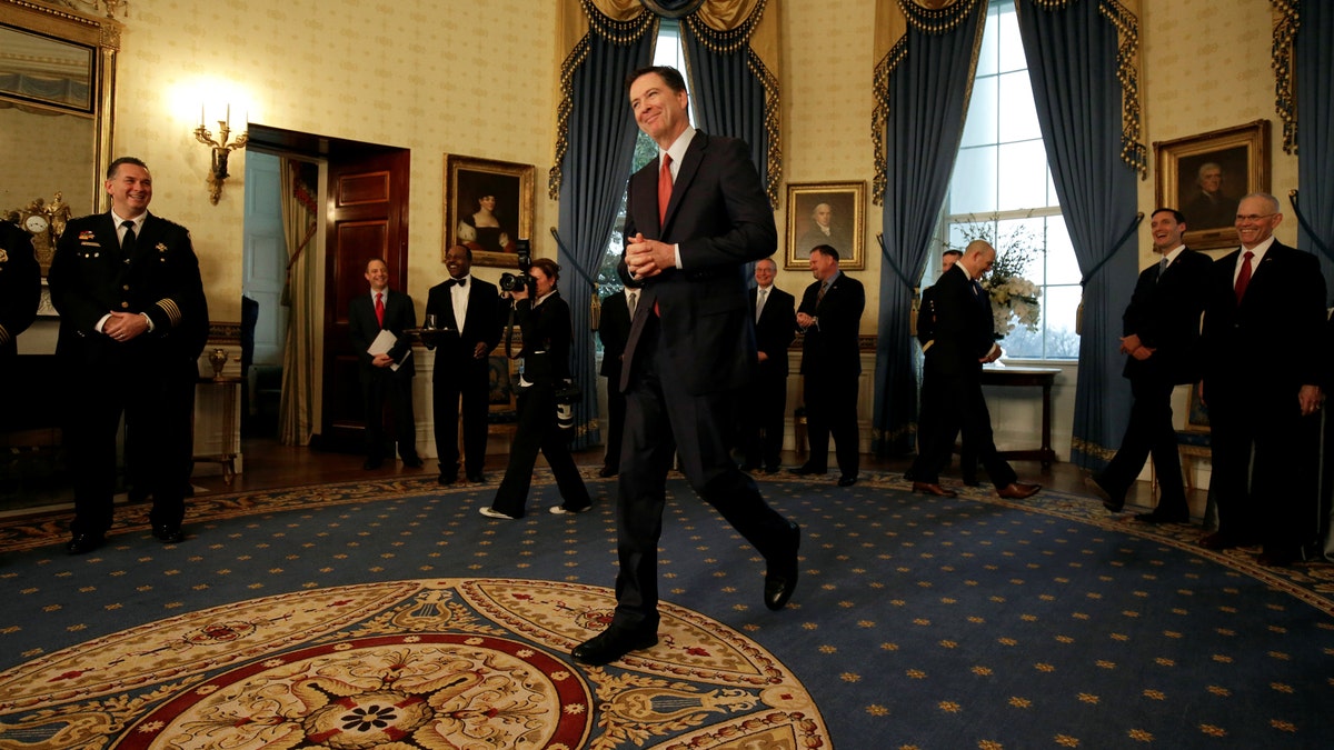 Director of the FBI James Comey walks to greet U.S. President Donald Trump during the Inaugural Law Enforcement Officers and First Responders Reception in the Blue Room of the White House in Washington, U.S., January 22, 2017. REUTERS/Joshua Roberts - RTSWV23