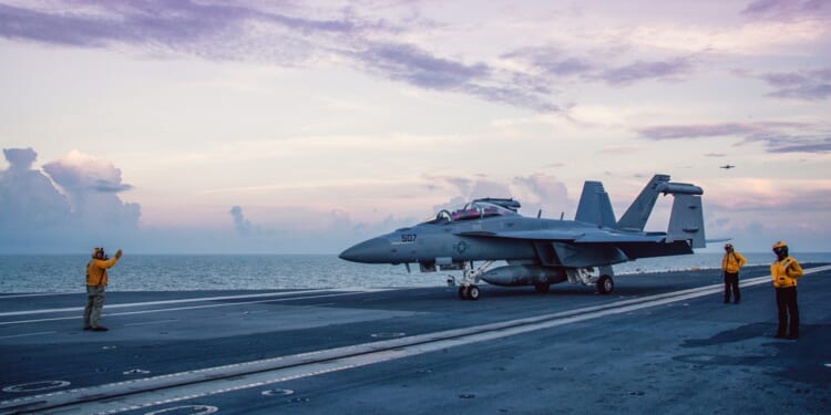 A fighter jet on an aircraft carrier deck.