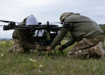 Two soldiers installing a munition on a large drone.
