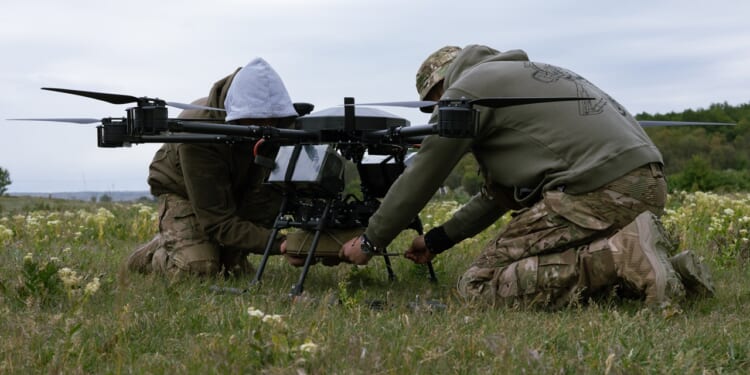Two soldiers installing a munition on a large drone.