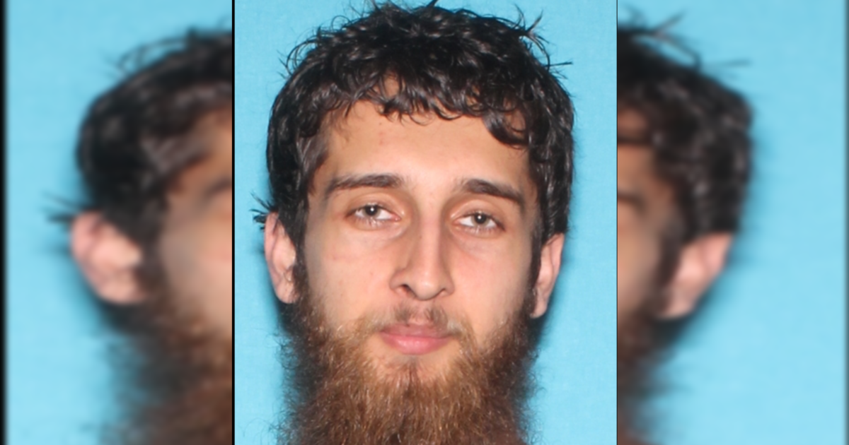 Image of a man with a beard and short, curly hair against a blue background, typically used for identification purposes.