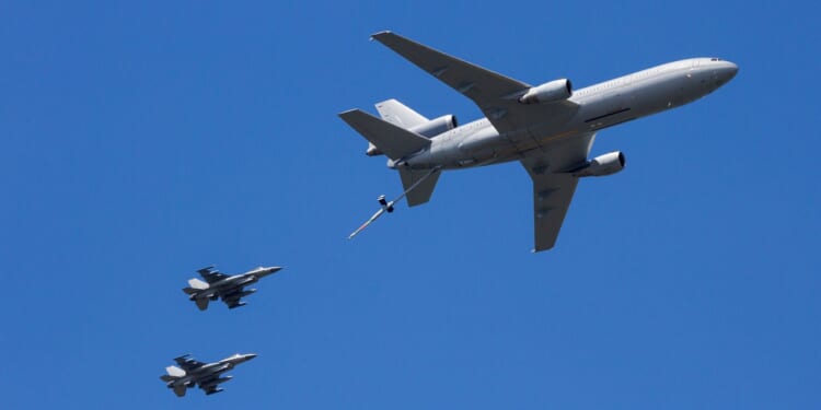 Two fighter jets conduct aerial refueling with a tanker.
