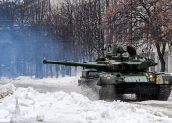 A tank firing its main gun in the snow.