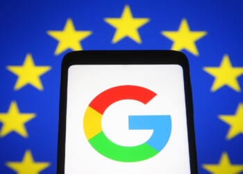 In this photo illustration Google logo is seen on a mobile phone screen in front of the European Union flag