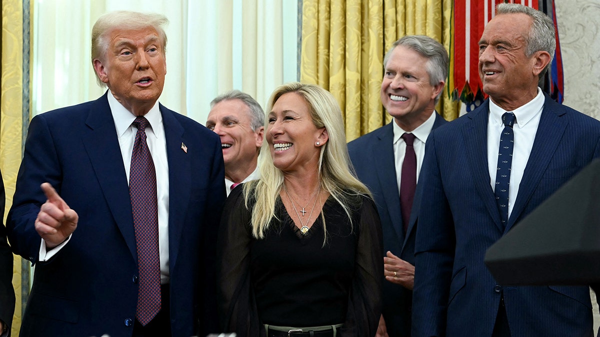 President Trump speaks as Marjorie Taylor Greene looks at him