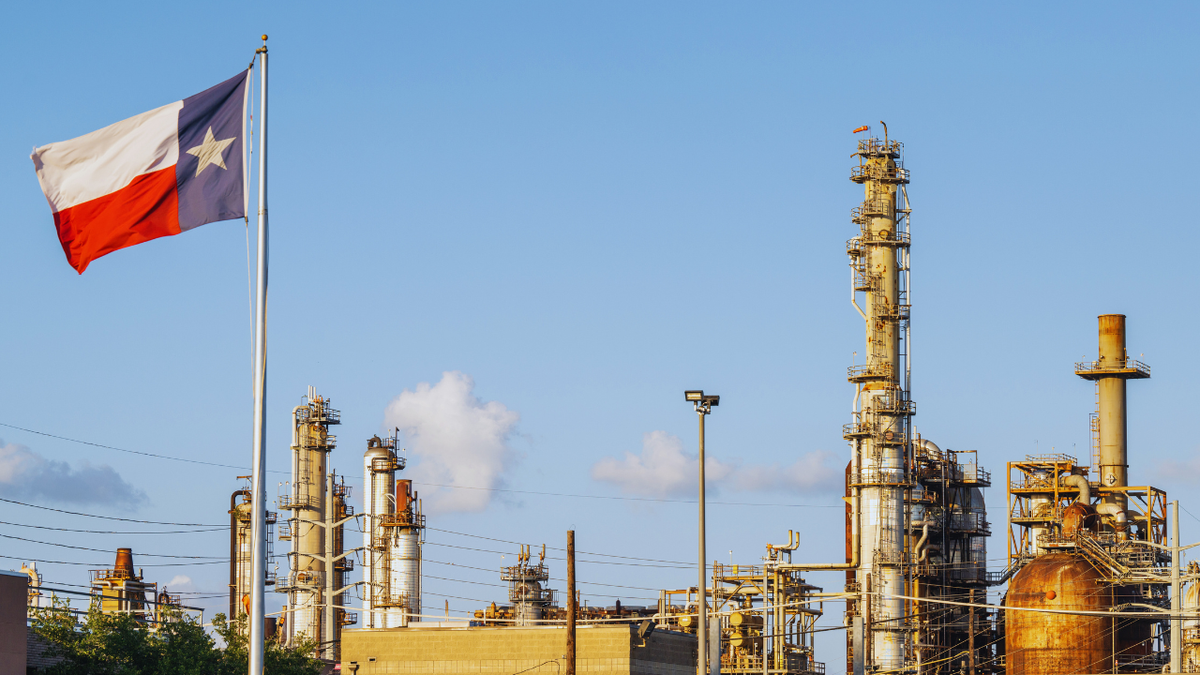 The Texas state flag flies over a Houston oil refinery.