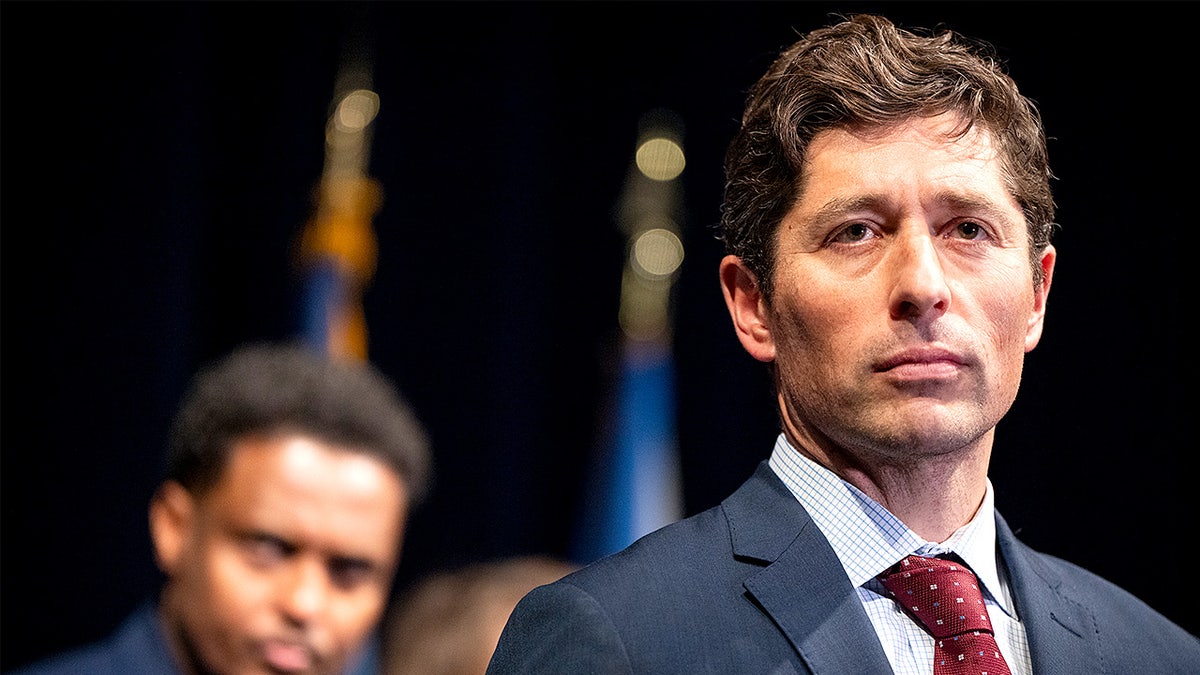 Minneapolis Mayor Jacob Frey speaks at a podium during a press conference with a city council member standing behind him.