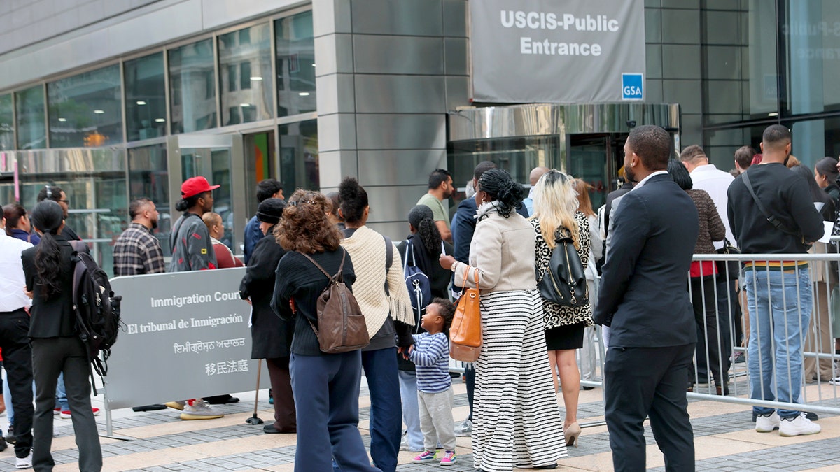 A line of people stands outside a federal courthouse waiting to pass through security.