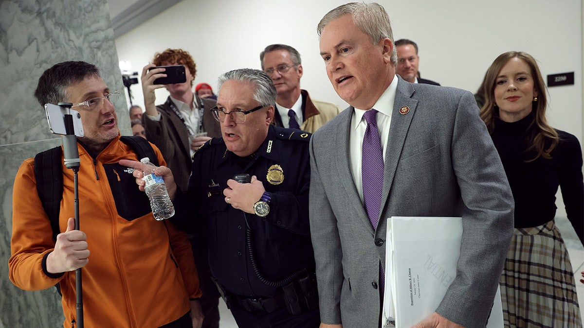 A protester attempts to accost James Comer in a hallway
