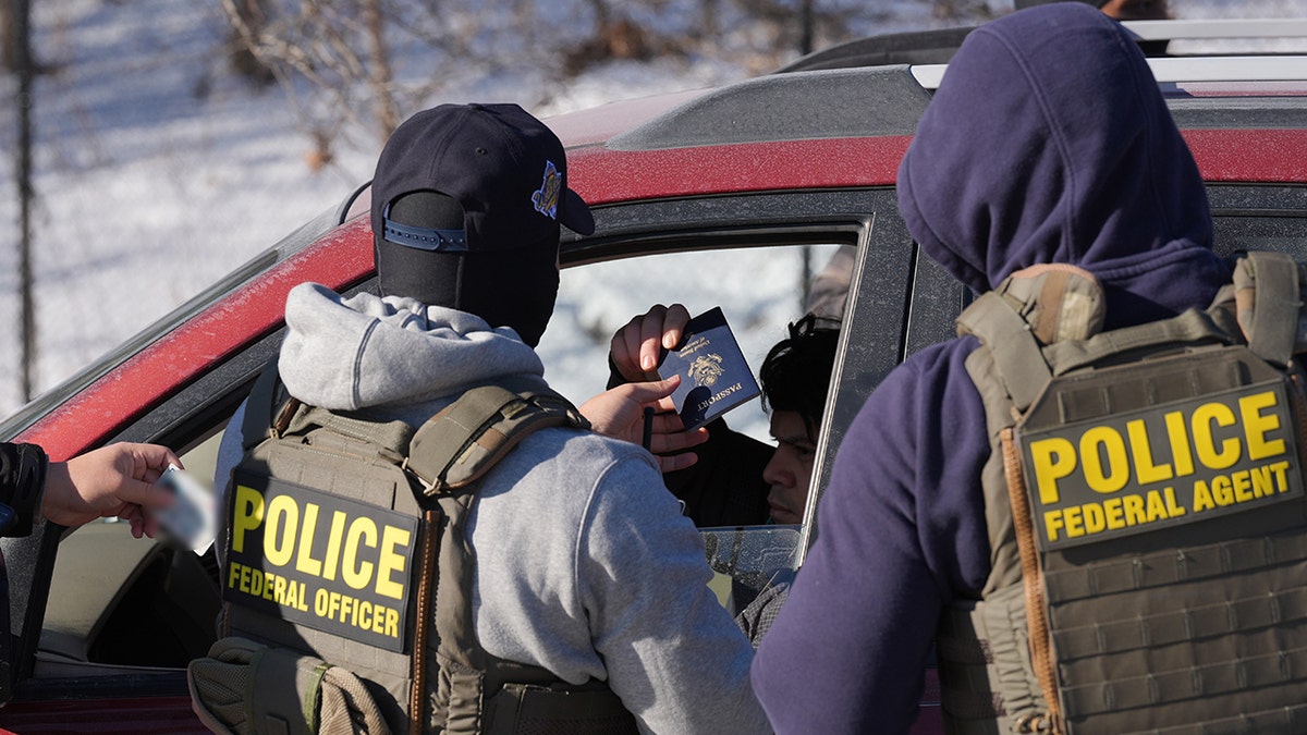 Federal agents conducting a traffic stop as a person holds out a passport and driver's license.