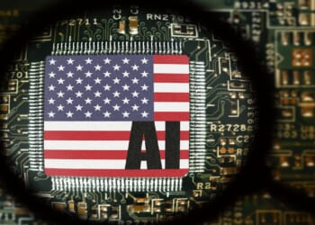 Flag of USA on a processor with word AI. Computer board with chip. View through magnifying glass