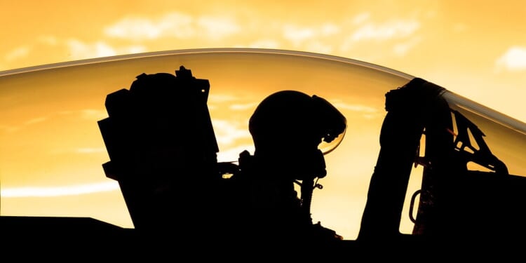The outline of a fighter pilot through the cockpit.