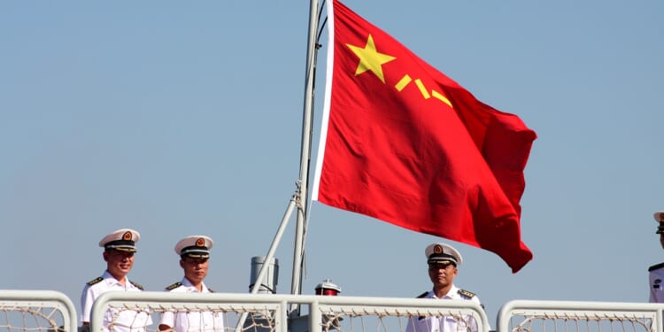 Chinese sailors under a People's Liberation Army Navy flag.