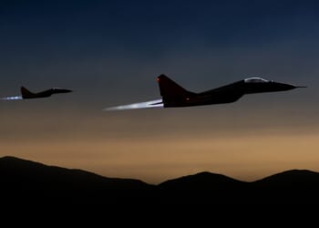 Two fighter jets flying at dusk.