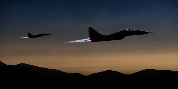 Two fighter jets flying at dusk.