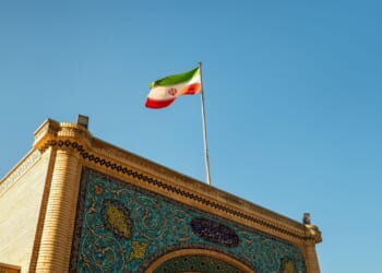 Iranian flag over ornate gate.