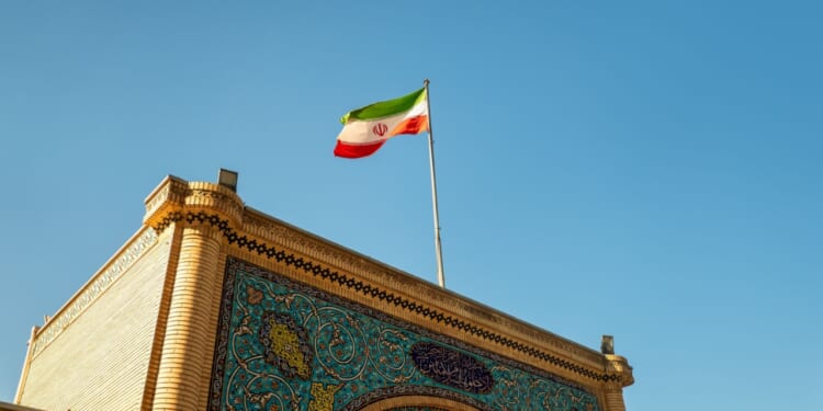 Iranian flag over ornate gate.