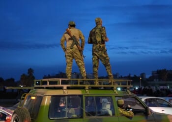 Syrian soldiers stand on a car.