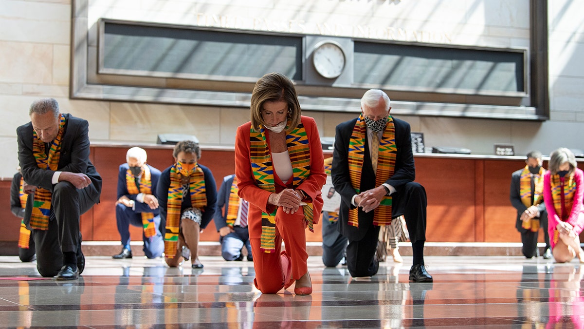 Democrats kneel wearing Ghanian kente cloth stoles