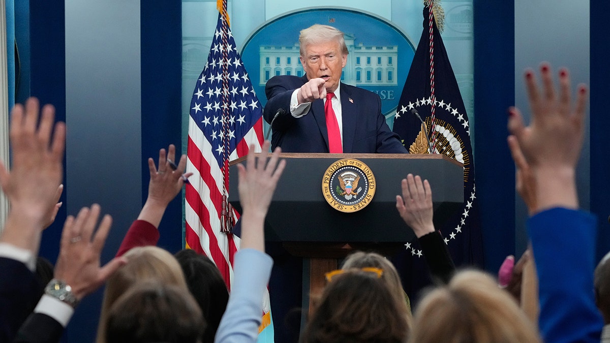 President Donald Trump gestures while calling on a reporter during a press briefing.
