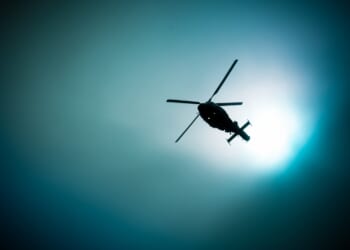 Military navy helicopter flying at night on the moon background.