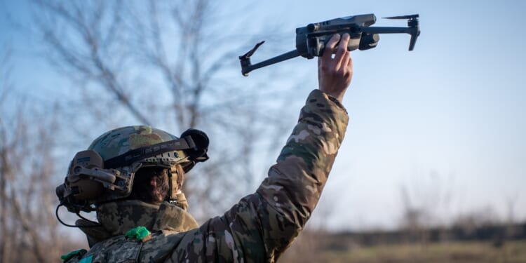 A Ukrainian soldier carrying a drone.