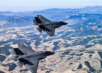 F-35s zoom over desert environment.