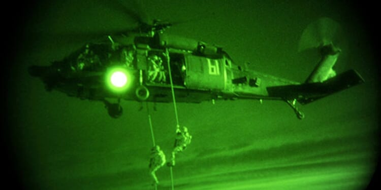 Two Delta Force soldiers descending from a helicopter.