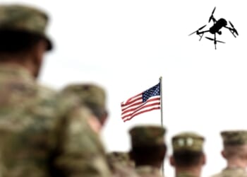 A group of US soldiers with a drone overhead.