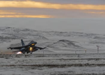 A fighter jet taking off from a snowy runway.