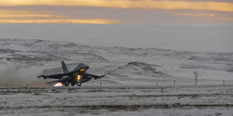 A fighter jet taking off from a snowy runway.
