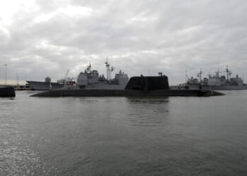 An Astute-class submarine near a naval yard.