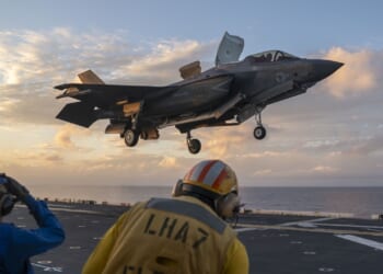 An F-35B fighter jet lands on the deck of an aircraft carrier.