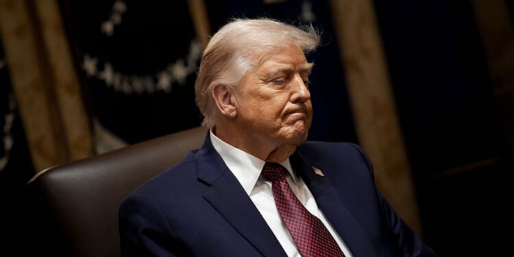 President Donald Trump looking down during a meeting at the White House.