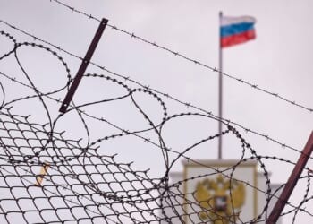 A Russian flag behind barbed wire.